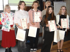 Cztery dziewczyny i kobieta stoją obok siebie. Dziewczyny trzymają w rękach dyplomy