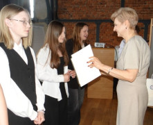 Moment wręczania dyplomów. Dyplomy uczestnikom konkursu wręcza kobieta