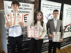 Dziewczyna i chłopiec stoją obok siebie. Wszyscy trzymają w dłoniach dyplomy