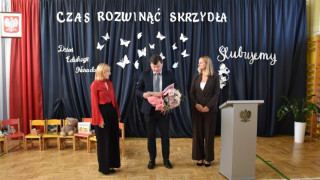 Dwie kobiety i mężczyzna stoją obok siebie. Mężczyzna trzyma w ręku bukiet kwiatów