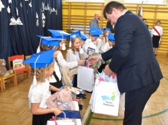 Dzieci i mężczyzna. Mężczyzna wręcza upominki pierwszoklasistom 