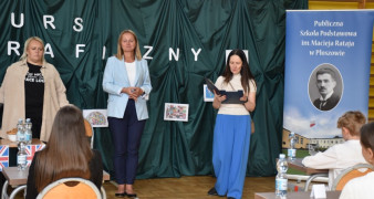 Trzy kobiety stoją obok siebie. Jedna z nich trzymając w dłoniach dokumenty przemawia 