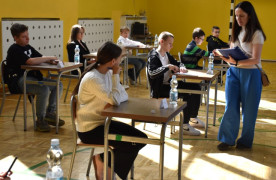 Kobieta rozdaje uczniom testy