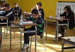 Uczniowie podczas konkursu. Siedzą w ławkach i rozwiązują test 