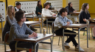 Młodzież siedzi przy szkolnych stolikach. Trwa matematyczny konkurs 