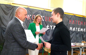 Chłopiec odbiera gratulacje od mężczyzny. Widoczna jest też kobieta w zielonej marynarce 