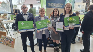 Cztery osoby stoją obok siebie. Są to trzy kobiety i jeden mężczyzna. Wszyscy trzymają w dłoniach dyplomy 