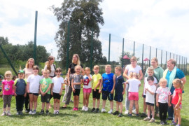 Grupa osób: dorośli i dzieci na trawiastym boisku 