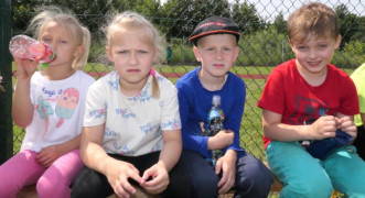 Dwie dziewczynki i dwaj chłopcy siedzą obok siebie na ławce