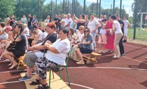 Dorośli siedzą na ławkach i obserwują występy dzieci 