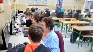 Dorośli i dzieci siedzą przy komputerach 