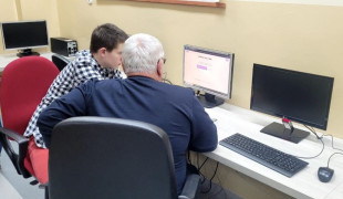 Senior i uczeń siedzą przy komputerze