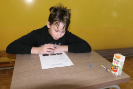 Chłopiec siedzi w ławce i rozwiązuje test