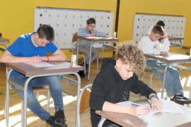 Uczestnicy konkursu pożarniczego. Dzieci siedzą w ławkach i rozwiązują test