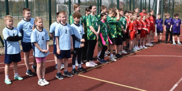 Grupa dzieci: dziewczęta i chłopcy w sportowych strojach stoją w szeregu 