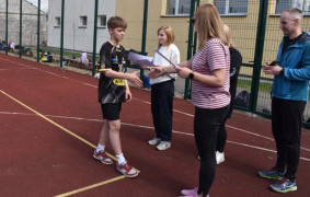 Kobieta wręcza dyplom chłopcu. 