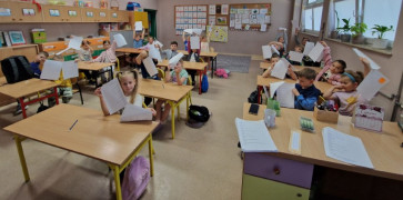 Dzieci siedzą w szkolnych ławkach 