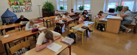 Dzieci siedzą w szkolnych ławkach 