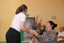 Dziewczynka wręcza kobiecie wrzos