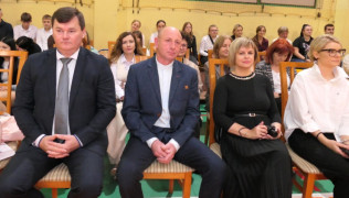 Cztery osoby siedzą obok siebie na krzesłach 