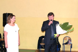 Mężczyzna trzyma w ręku kwiaty. Obok stoi kobieta