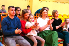 Grupa osób siedząca na krzesłach i klaszcząca w ręce 