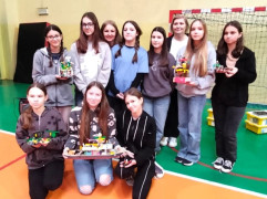 Grupa dziewczyn stoi obok siebie. Dziewczyny prezentują modele, które ułożyły z klocków lego