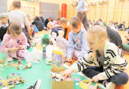 Uczniowie siedzą na podłodze i układają klocki lego
