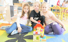 Trzy dziewczynki prezentują domek, który ułożyły z klocków lego
