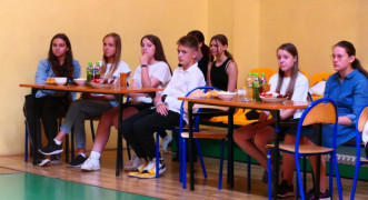Grupa dzieci siedząca w ławkach 