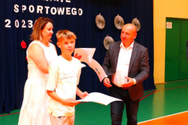 Trzy osoby: kobieta, mężczyzna i chłopiec. Chłopiec trzyma w ręku dyplom 