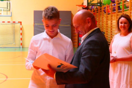 Chłopiec z rąk mężczyzny odbiera dyplom 