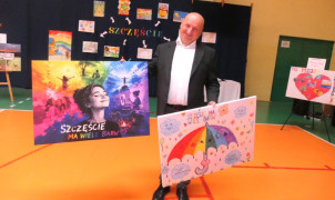 Mężczyzna trzyma w dłoniach dwa konkursowe plakaty