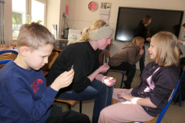 Kobieta i dwoje dzieci siedzą obok siebie i rozmawiają 