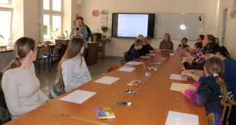 Grupa osób siedzi przy stole. Trwają warsztaty plastyczne 