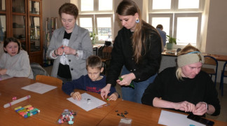 Dwie kobiety tłumaczą uczestnikom warsztatów jak wykonać ozdoby z gliny polimerowej 