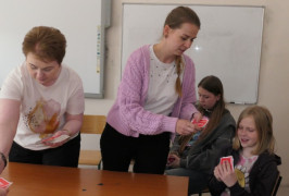 Dwie kobiety i dwie dziewczynki. Kobiety dają dziewczynkom karty 