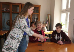 Kobieta przekazuje kartki kobiecie i chłopu, którzy siedzą w ławce