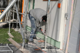Mężczyzna podczas prac budowlanych. Trwa remont elewacji budynku 