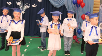 Grupa dzieci w granatowych biretach na głowie