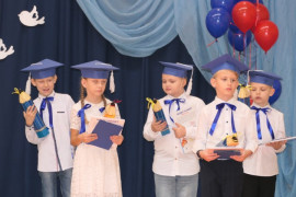 Grupa dzieci w granatowych biretach na głowie 