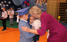 Dziewczynka i chłopiec wręczają kwiaty kobiecie