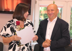Kobieta i mężczyzna. Kobieta trzyma w ręku czerwoną różę i dokumenty. 