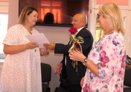 Dwie kobiety i mężczyzna. Moment wręczania dokumentów z okazji awansu zawodowego
