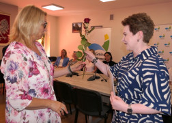 Dwie kobiety. Jedna z nich wręcza różę 