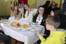 Dziewczynki i chłopiec siedzą przy stoliku 