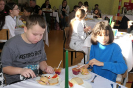 Dwaj chłopcy siedzą przy stole i jedzą kanapki