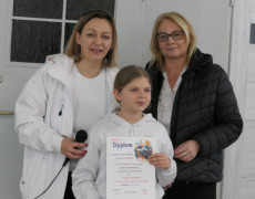 Dwie kobiety i dziewczynka. Dziewczynka trzyma w ręku dyplom 