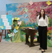 Dziewczyna w białej bluzce i czarnych spodniach stoi i recytuje wiersz 