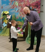 Mężczyzna wręcza dyplom małemu chłopcu 